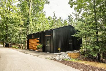 Modern black metal building in a forest.