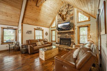 Cozy rustic living room with leather sofas and stone fireplace.