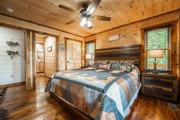 Cozy wooden cabin bedroom with a large bed and ceiling fan.