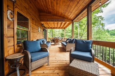 Cozy wooden porch with blue cushioned wicker furniture.