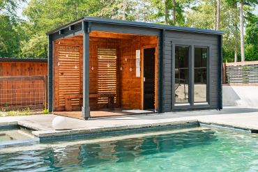 Modern poolside sauna with wooden walls and glass doors.