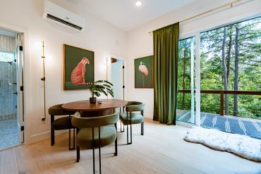 Modern dining room with large windows and green accents.