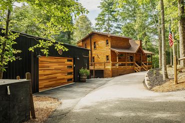 Cozy wooden cabin with a modern garage in a forest setting.