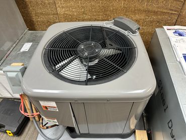 A gray air conditioning unit with a large fan on top placed indoors.