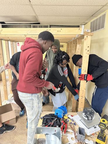A group of young people working together on a woodworking project indoors.