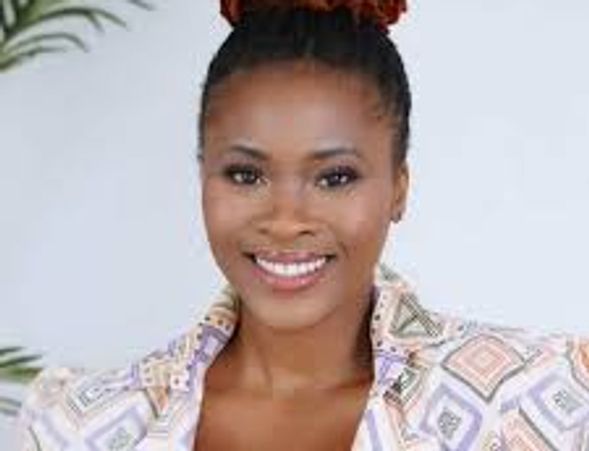 Smiling woman with braided hair and patterned blouse.