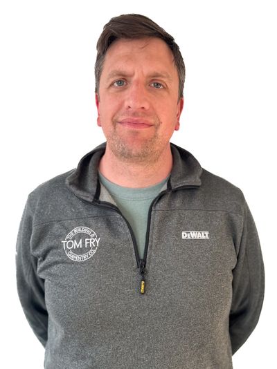 Man wearing a gray zip-up sweater with Tom Fry and DeWalt logos.
