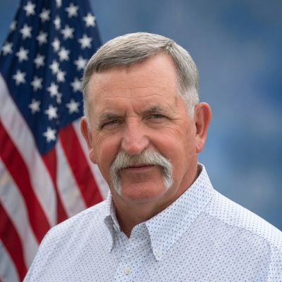 Portrait of a man with a mustache in front of an American flag.
