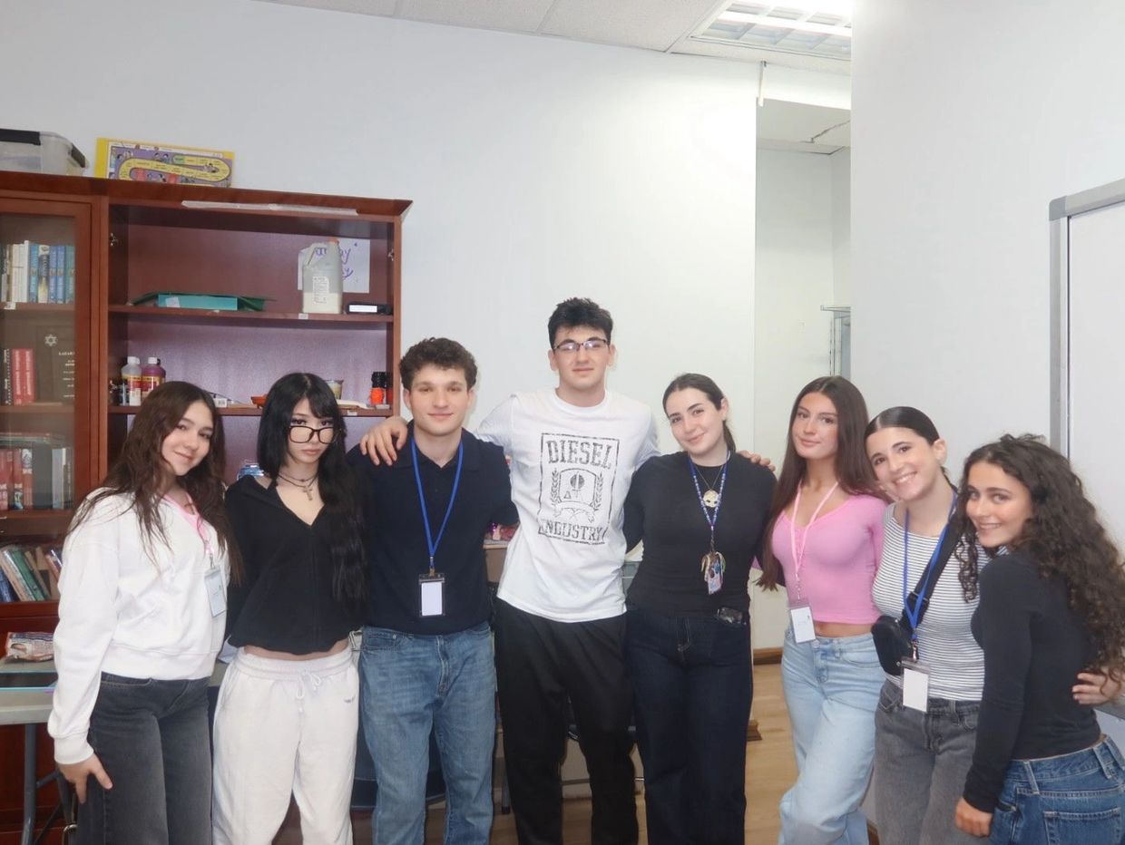 A group of eight young adults posing together indoors, smiling.