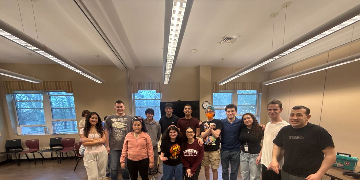 A diverse group of people posing together in a classroom.