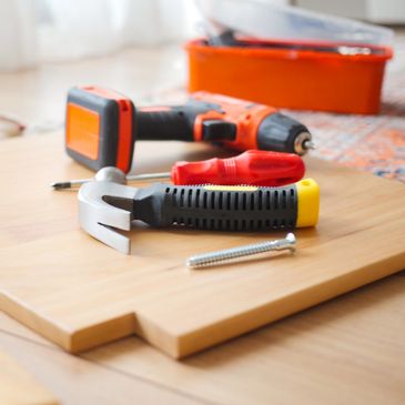 Hand tools and drill on wooden surface.