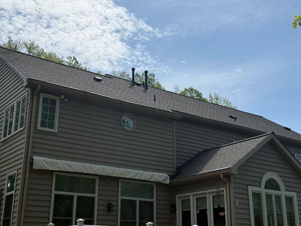Modern two-story house exterior with gray siding and multiple windows under a partly cloudy sky.