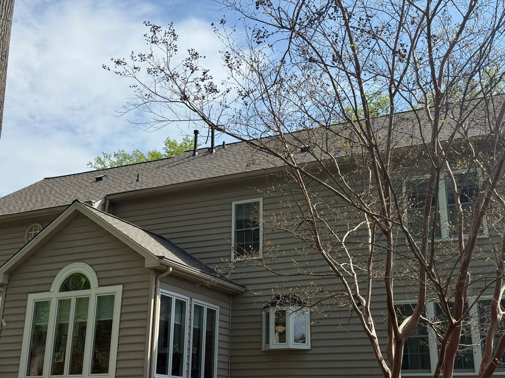 Large beige house with leafless trees in the foreground.