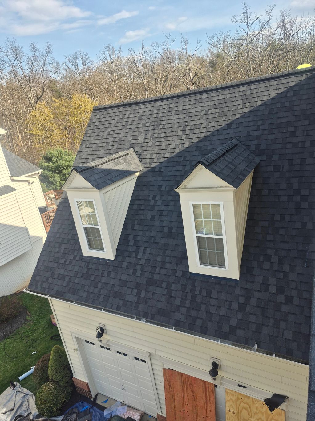 Two dormer windows on a dark gray shingled roof of a house.