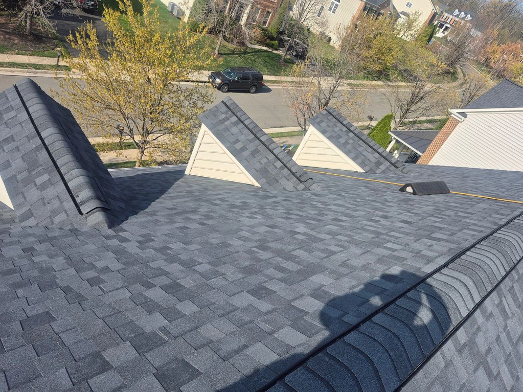 Newly shingled roof with neat dormer windows overlooking a suburban street.