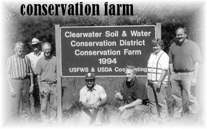 Black and white photo of old board and staff members around farm sign