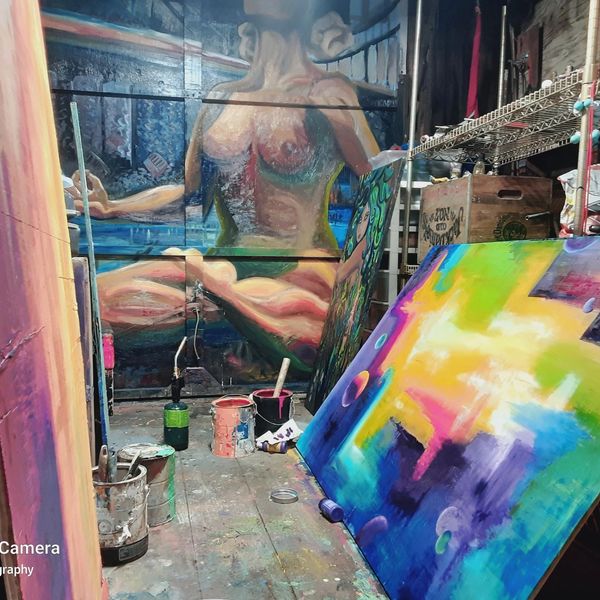Woman in yoga pose mural by Artist Lindsey Bryant surrounded by paintings in element art studio
