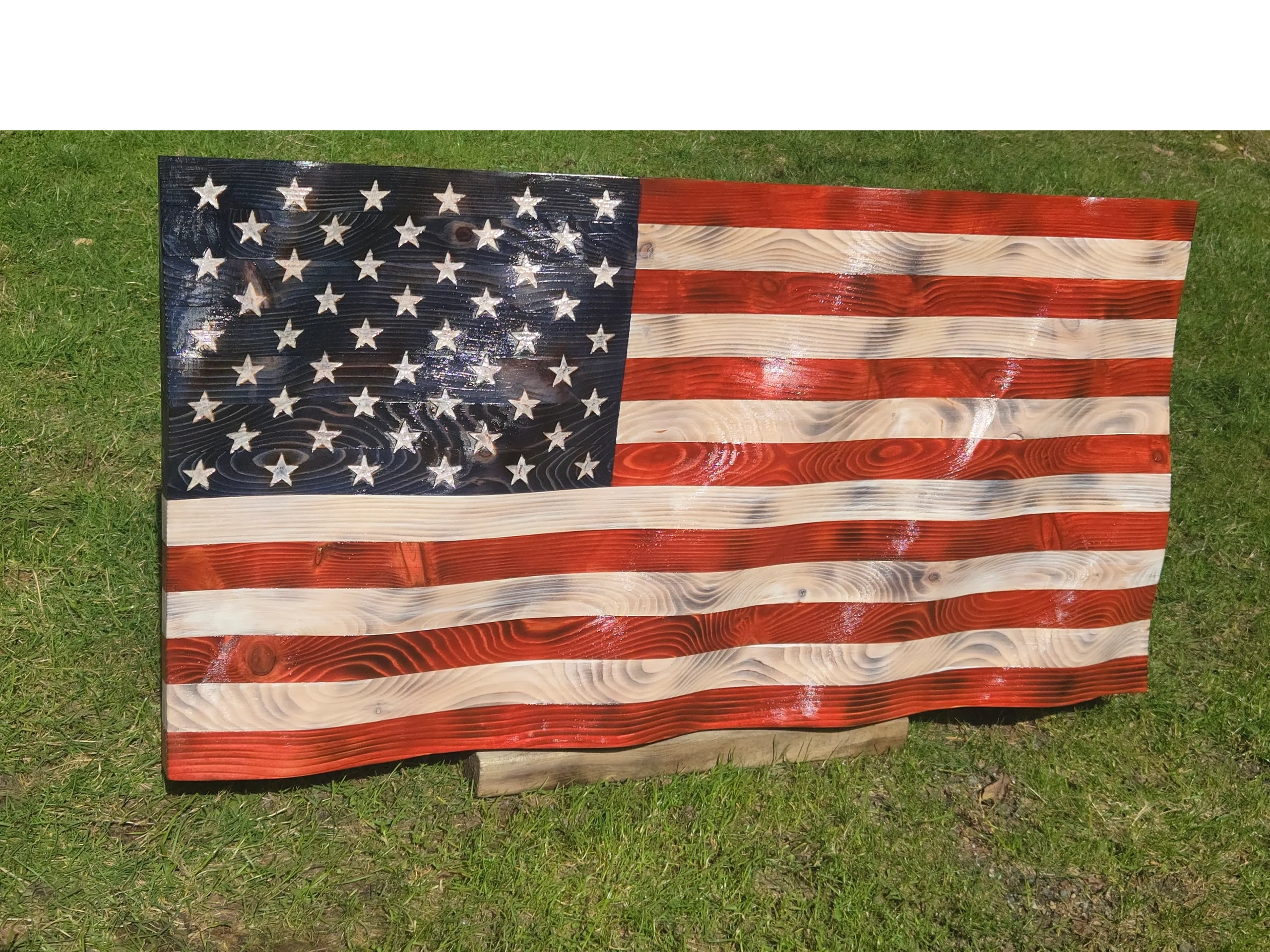 Wooden American flag on grass.