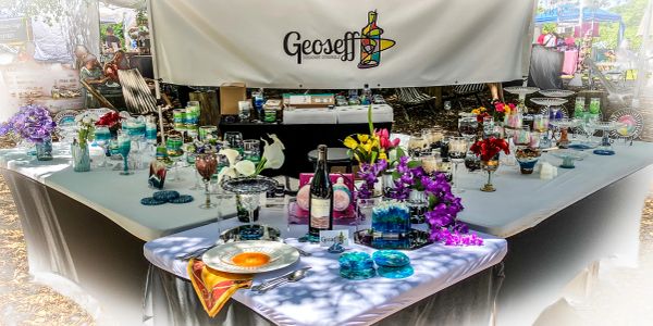 Outdoor table display of glassware and decorations at Geoseff booth.