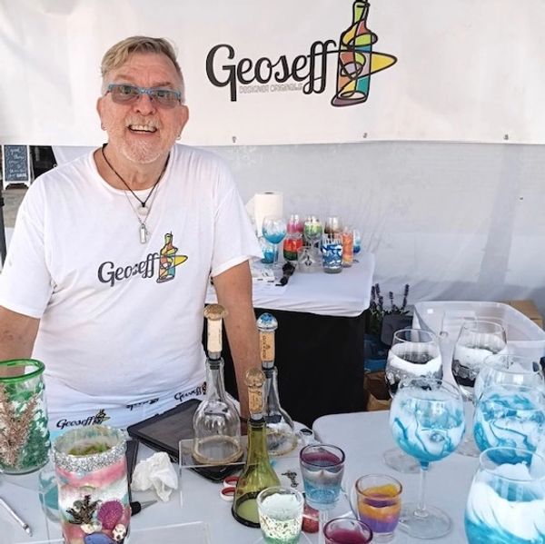 Man smiling at a booth with colorful glassware.