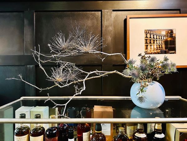 Ikebana arrangement in blue round vase on a liquor cabinet with whiskies 