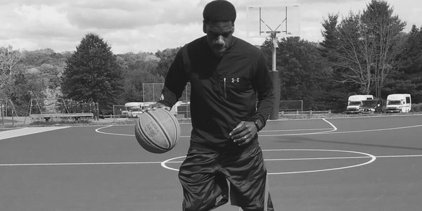 Man dribbling basketball on outdoor court.