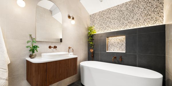 Modern bathroom with a freestanding tub and wooden vanity.