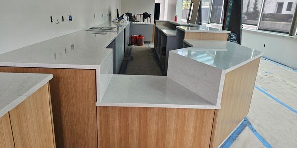 Modern kitchen counters with wood cabinets and marble tops under construction.