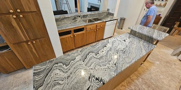 Newly installed granite countertops with intricate black and white patterns in a kitchen.