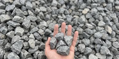 Hand holding gray crushed stones over a pile.