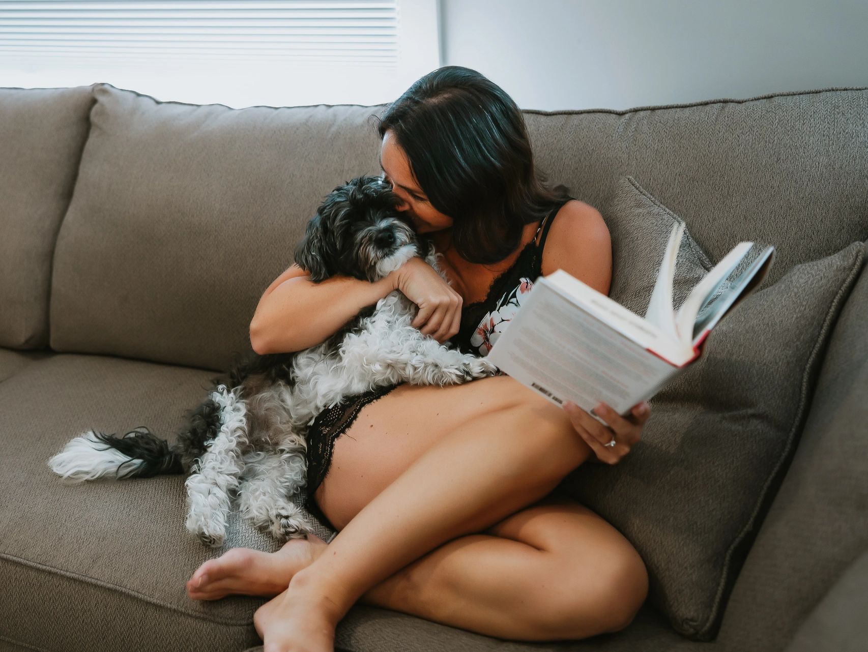 Annette Bruneau and her puppy snuggling on the couch, reading a book.