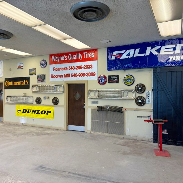 Interior wall of a tire shop with various tire brand signs and car parts.