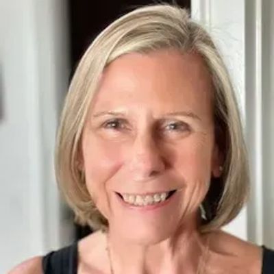 Smiling middle-aged woman with short blonde hair in a black top.