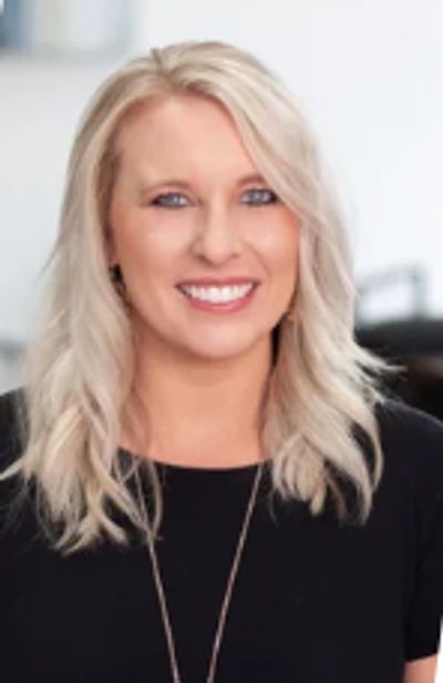 Smiling woman with blonde hair wearing a black top.