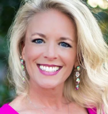 Smiling woman with long blonde hair and colorful earrings.