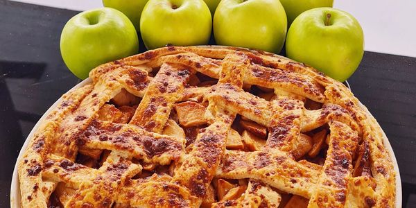 A golden, flaky apple pie fresh from the oven, with warm cinnamon-spiced apples bubbling beneath the perfectly crimped crust.