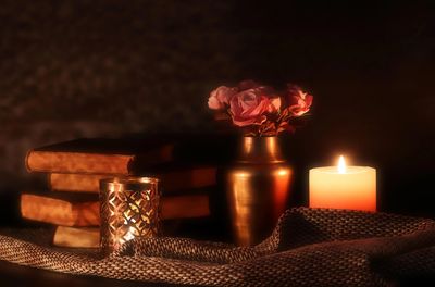 Cozy arrangement of books, candles, and flowers on a soft fabric.