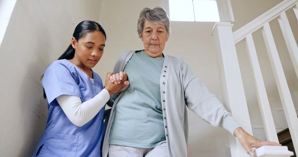 Senior woman, nurse and help on stairs, retirement home and caregiver for support