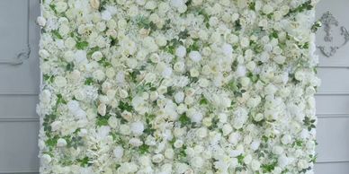 A beautiful 10 x 10 white flower wall with organic greenery from weddings to baby showers 