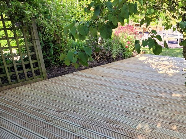 Wooden deck surrounded by greenery and flowers.
