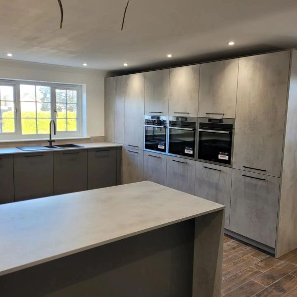 Modern kitchen with grey cabinets and built-in ovens.