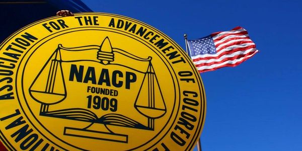 NAACP emblem with American flag against clear blue sky.