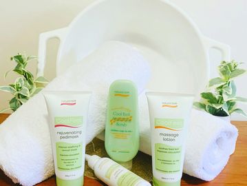 Spa skincare products with white towels and green plants on wooden surface.