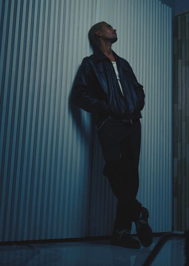 Man leaning against a wall in a dark setting.