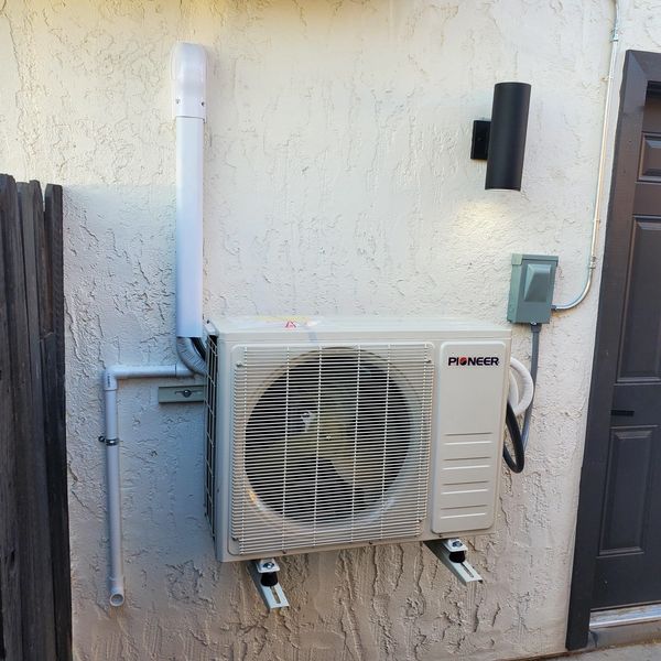 Wall-mounted Pioneer air conditioning unit with piping and outdoor light.