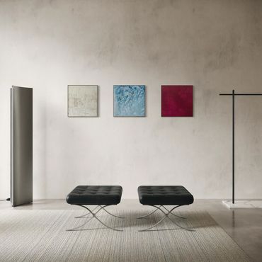 Minimalist room with two black stools and three small abstract paintings.