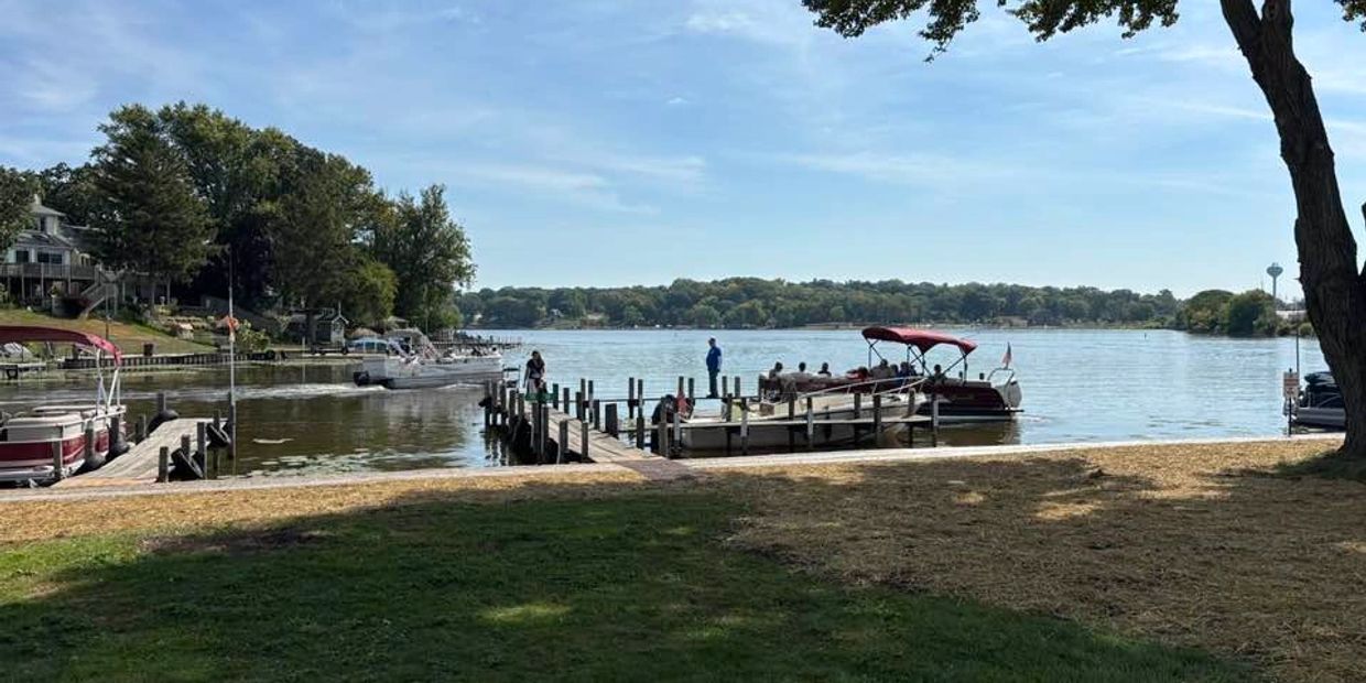 People enjoying a sunny day by the lake with boats docked at piers.