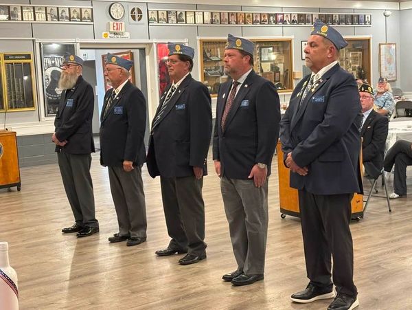 Veterans standing in uniform during a ceremony in a hall.