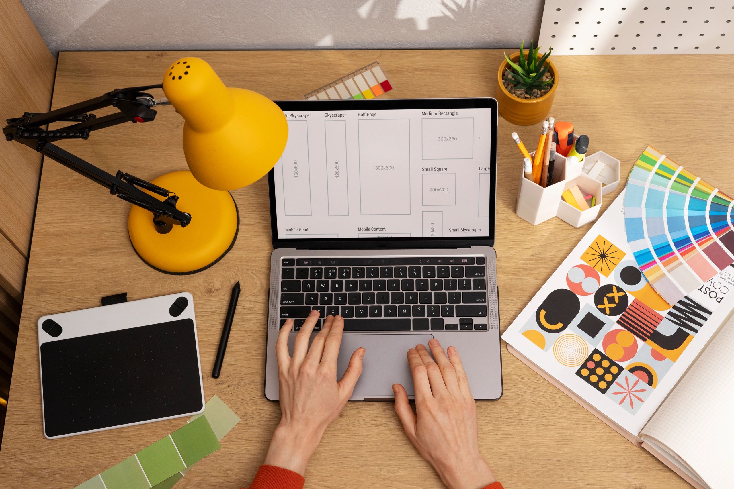 Persona trabajando en un portátil con herramientas de diseño gráfico.
