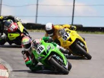 Three motorcyclists racing on a curved track, leaning into the turn.